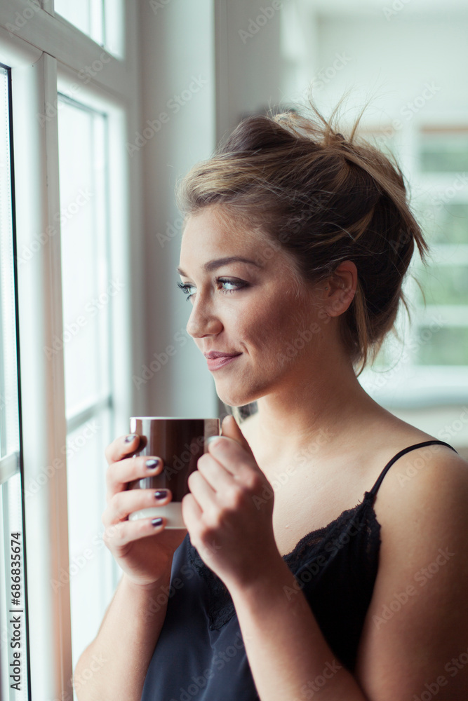 Portrait of smiling blond woman with glass of coffee looking through window Portrait of smiling blond woman with glass of coffee looking through window