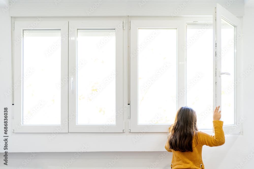 Girl opening window and looking out while standing at home Girl opening window and looking out while standing at home