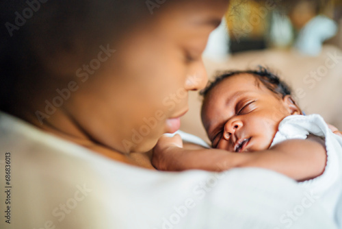 Close-up of mother carrying sleeping newborn daughter at home