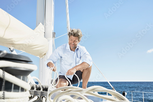 Mature man working with ropes on sailing boat