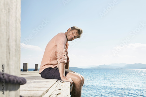 Smiling man sitting on jetty