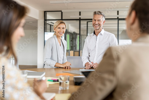 Smiling businesswoman and businessman leading a meeting in office photo