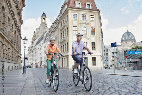 Senior tourists riding electric bicycle against Frauenkirche Cathedral at Dresden, Germany