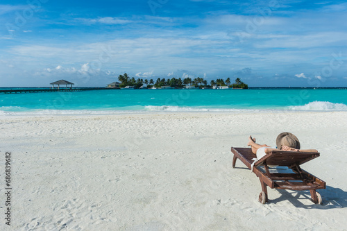 Maledives, Ari Atoll, Nalaguraidhoo, Sun Island Resort, back view of woman relaxing on the beach photo