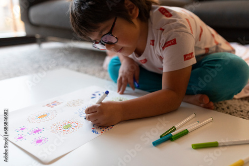 Boy sitting on the floor at home drawing flowers