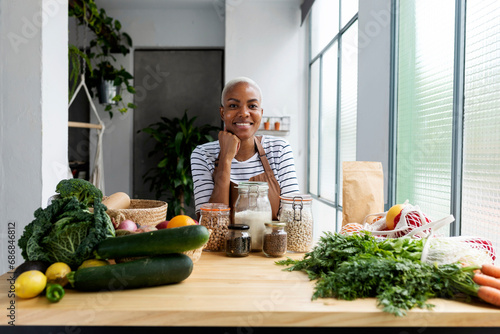 Murais de parede Woman with apron in kitchen , unpacking freshly bought organic fruit and vegetab