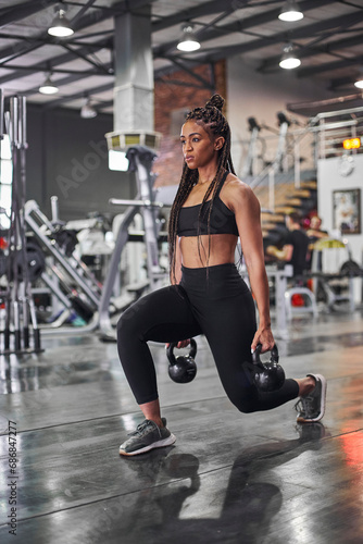 Female athlete doing lunges with kettlebells