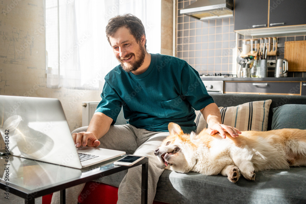 Portrait of smiling man sitting on couch at home using laptop