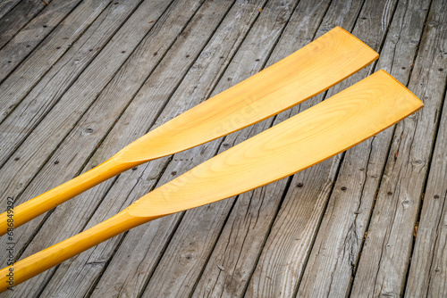Fototapeta blades of wooden rowing oars against rustic, grunge wood deck