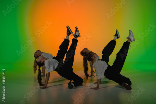 In the frame on a green, gradient background in the spotlight. A group of attractive, young girls is dancing. They demonstrate various dance moves in the direction of jazz funk.