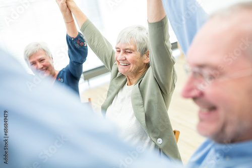 Group of seniors practicing chair gymnastics with instructor in retirement home photo