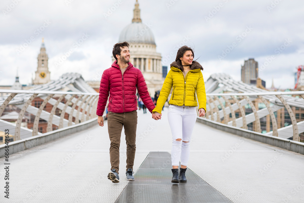 UK, London, young couple walking hand in hand on bridge in front of St Pauls Cathedral