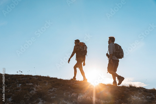 Italy, Monte Nerone, two men hiking in mountains at sunset photo