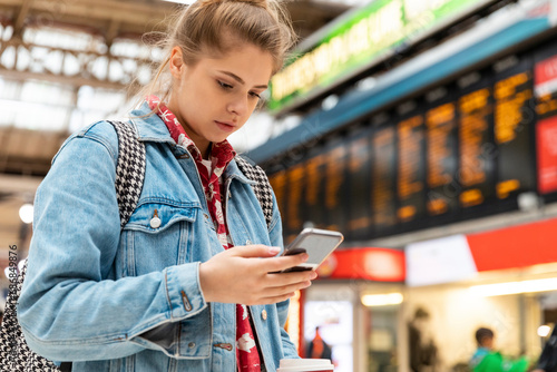 Young woman checking smartphone at the train station photo