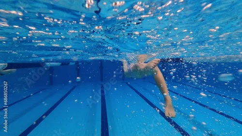 Leg movement (kicking legs ) of the young girl backstroke swimming. Underwater rear view.