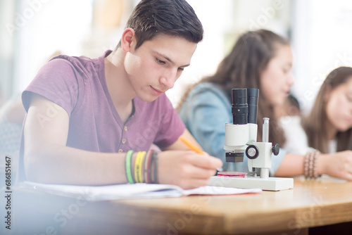 Science student working in class with microscope photo