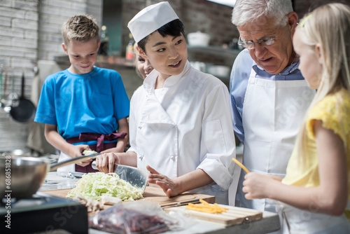 Female chef instructing kids in cooking class photo