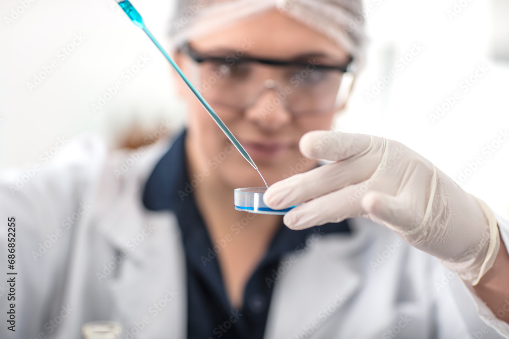 Scientist working in lab with pipet and petri dish Scientist working in lab with pipet and petri dish