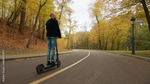 Wallpaper Mural Wonderful peaceful ride on eco friendly e-scooter along the road with multicolored old-growth trees, lawns and hills with thick blanket of yellow leaves. High quality 4k footage Torontodigital.ca