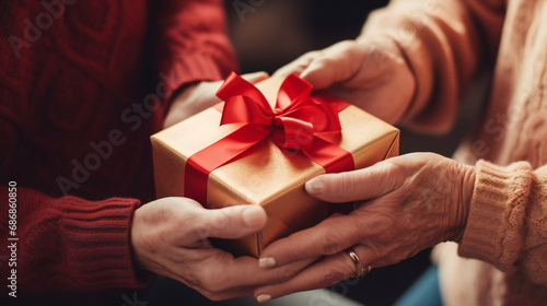Close up of elderly woman's hands holding present, receiving wrapped gift box from young daughter or grandchild