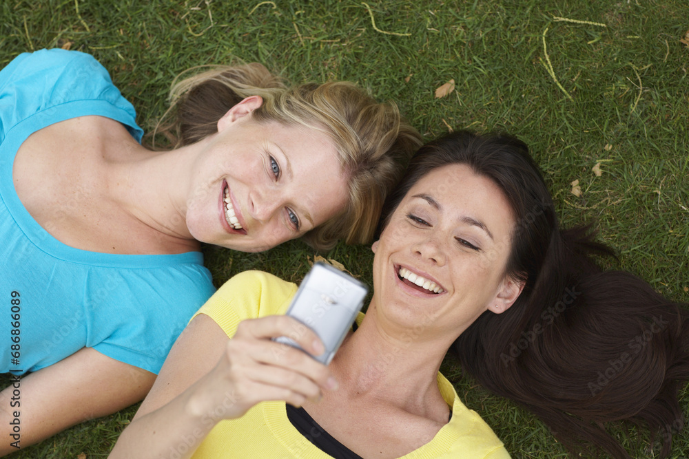 Friends Looking at Cellular Phone Outdoors Friends Looking at Cellular Phone Outdoors
