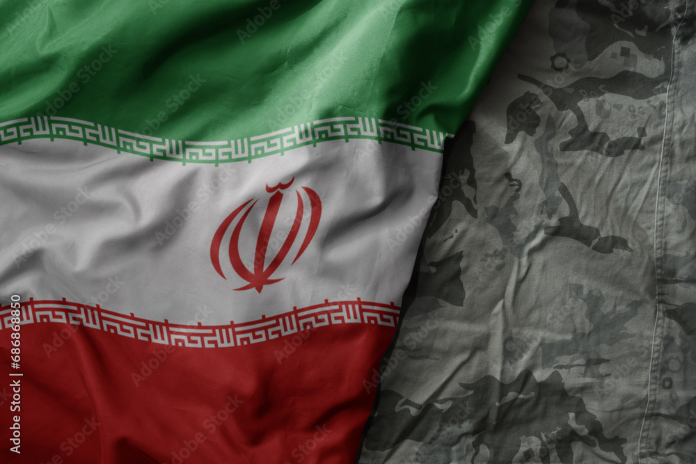 waving flag of iran on the old khaki texture background. military concept.