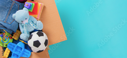 Foto Donations box with kid toys, books, clothing for charity on light blue background