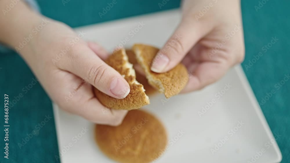 Young hispanic woman breaking a cookie at dinning room Young hispanic woman breaking a cookie at dinning room