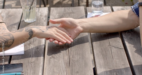 Young woman hands are adorned with tattoos. Tattoos on her hands can be a form of self-expression, artistry, or personal symbolism. Nonverbal communication. Close-up shot of couple hands on a date. 