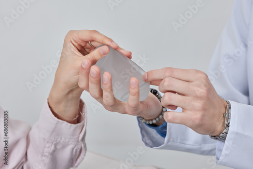 Professional plastic surgeon showing silicone breast implants to his female patient, mastopexy concept, BREAST LIFT photo