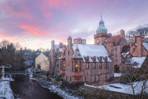 Quaint and historic Dean Village covered in snow along the Water of Leith during a winter sunset in Edinburgh, Scotland.