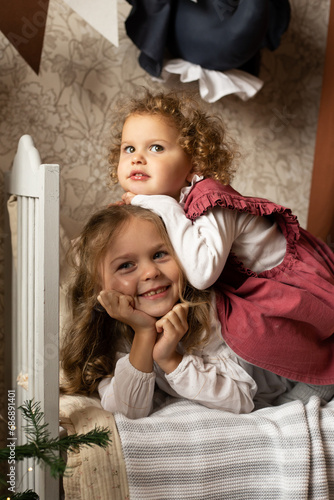 Two sisters playing lying on bed in children's room at home with toy animals