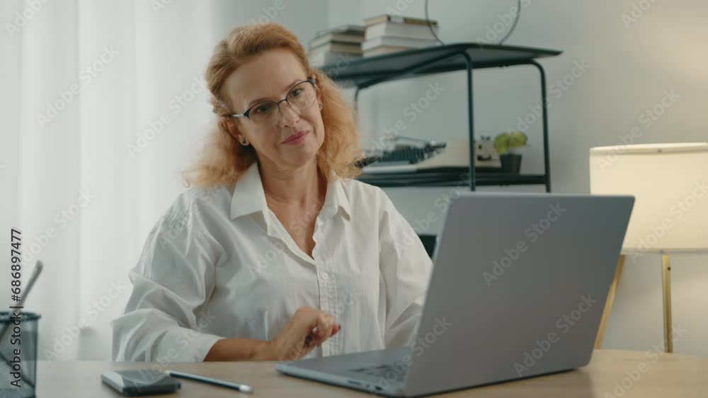 Beautiful well-groomed blonde woman in glasses finishes typing on laptop, closes lit and walks away form her workplace in a room with modern renovation. High quality 4k footage Beautiful well-groomed blonde woman in glasses finishes typing on laptop, closes lit and walks away form her workplace in a room with modern renovation. High quality 4k footage