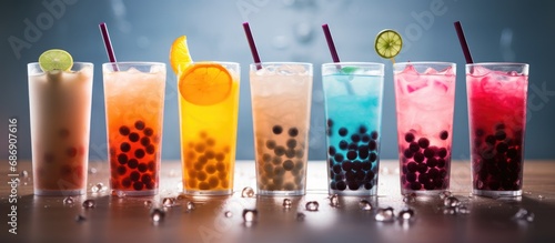 Colorful drinks with tapioca bubbles in transparent glasses against a lit background photo