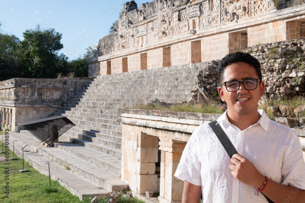 Young Latino tourist poses looking at the camera for a photograph in the nuns' quadrangle at the archaeological site of Uxmal in Yucatan, Mexico