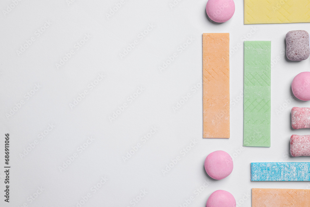 Fototapeta premium Different tasty colorful bubble gums on white background, flat lay. Space for text