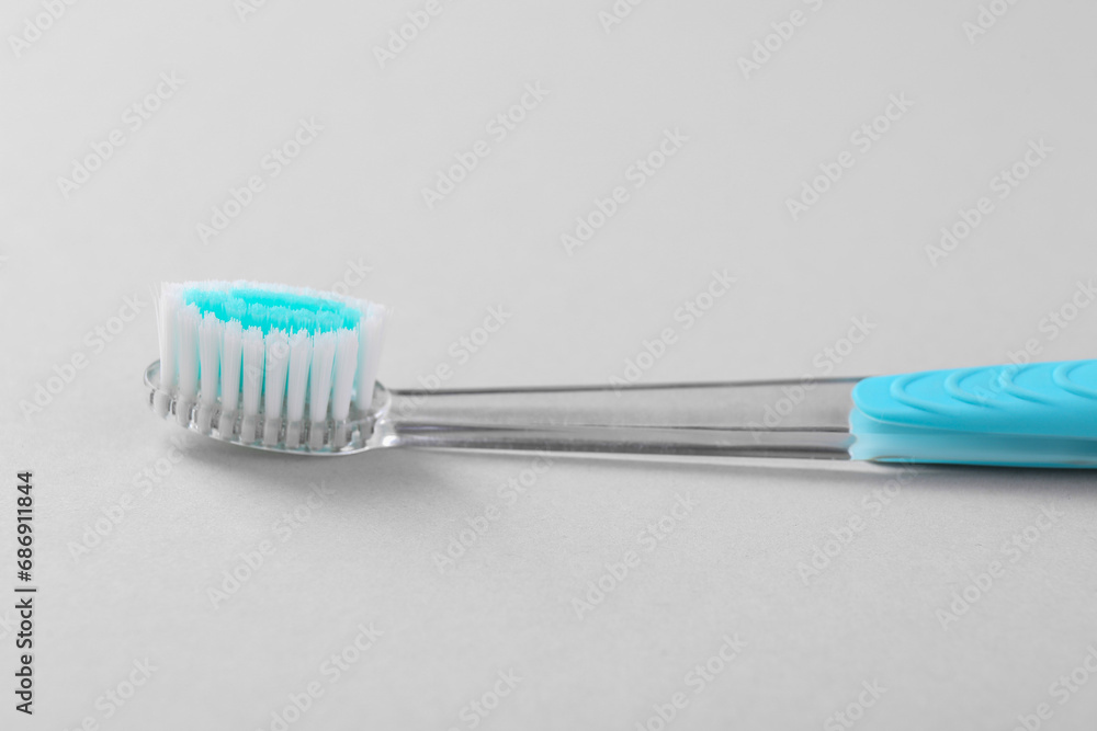 One plastic toothbrush on light background, closeup One plastic toothbrush on light background, closeup