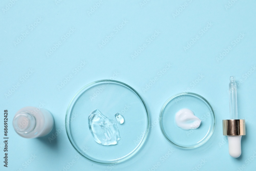 Petri dishes with samples of cosmetic serums, bottle and pipette on light blue background, flat lay. Space for text Petri dishes with samples of cosmetic serums, bottle and pipette on light blue background, flat lay. Space for text