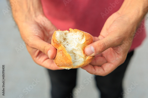 A man's hand holds a round bun, snack and fast food concept. Selective focus on hands with blurred background