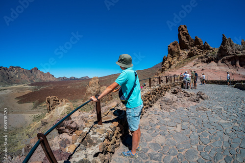 A teenager looks at the lava fields of Las Canadas caldera of Teide volcano and rock formations - Roques de Garcia. Tenerife. Canary Islands. Spain. Wide angle lens.