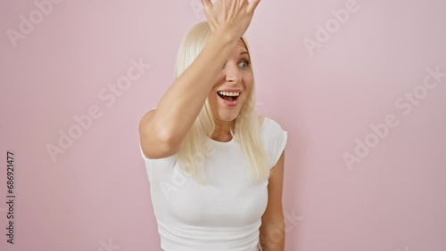 Oops! young, distressed blonde woman caught in a major blunder. hand on head, utter regret over mistake realized. isolated over pink, signaling a memory fail. photo