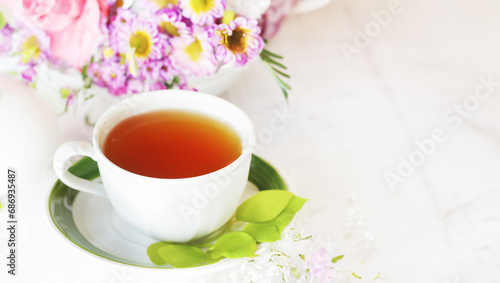 herbal tea in a cup, fresh flowers in the background, morning tea or herbal medicine concept