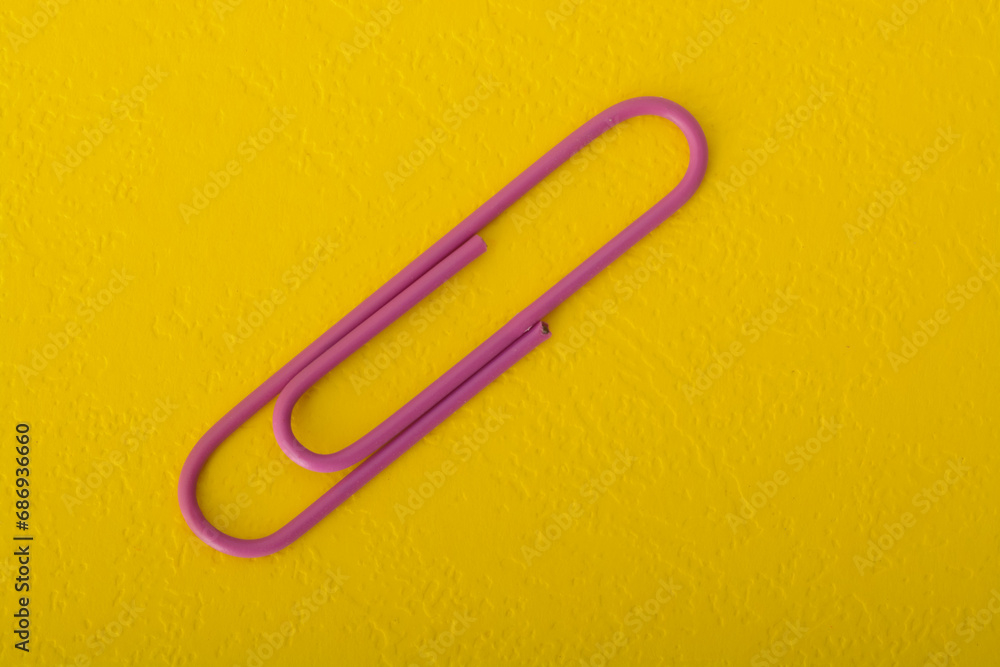 Purple paper clip isolated on a yellow background. Purple paper clip isolated on a yellow background.