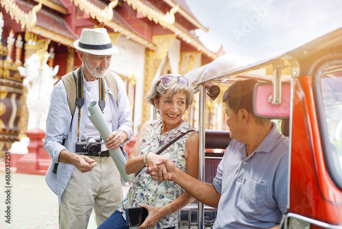 European senior tourist woman are congratulatory handshake with the Tuktuk Thailand taxi driver on Thai temple background. Senior tourist concept