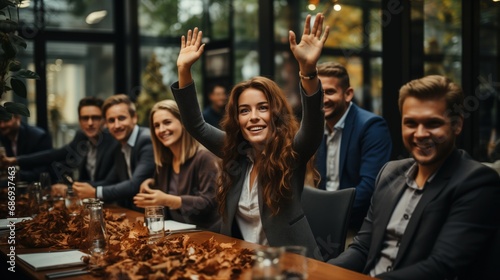 A group of people are gathered around a table strewn with autumn leaves, woman in the center raises her hands with excitement, signifying a joyful celebration or team success, corporate event, team