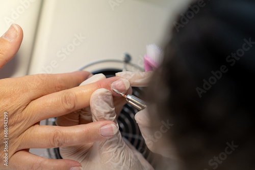 Nail care procedure in a beauty salon. Female hands and tools for manicure, process of performing manicure in beauty salon. Gloved hands of a skilled manicurist cutting cuticles. Concept spa body care