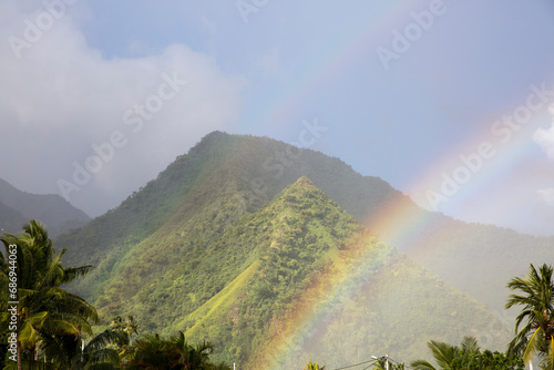 A colorful rainbow over the beach mountains at sunset in Tahiti 