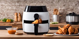 Air fryer cooking machine and french fries, fried chicken on table in kitchen.
