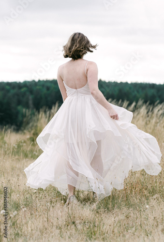 Obraz na plátně Bride running in dress through a field
