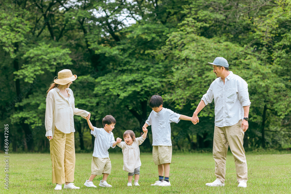 Fototapeta premium 夏休みに公園を手を繋いで歩く家族・ファミリー(レジャー・アウトドア・ピクニック・キャンプ・思い出)